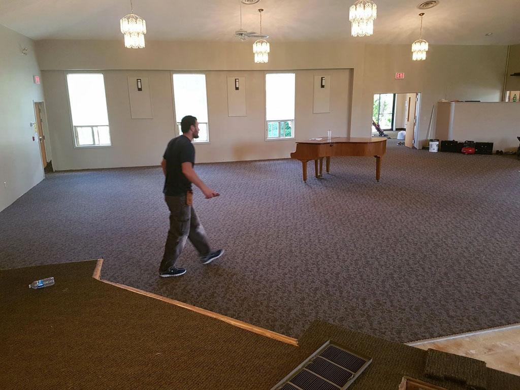 An El Nino Carpet and Flooring professional walking over commercial carpet being installed for a customer at a commercial property